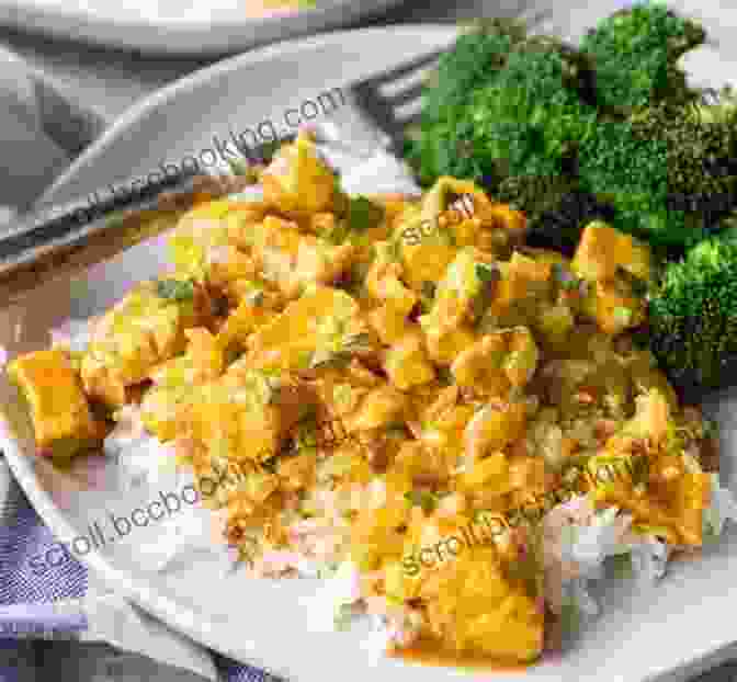 A Plate Of Tender Chicken Nestled In A Rich And Flavorful Coconut Curry Sauce Adorned With Fresh Cilantro, Served With Fluffy Basmati Rice On A Wooden Table. Decadent Coconut Dessert Cookbook: Recipes To Make Coconut Sweet Treats